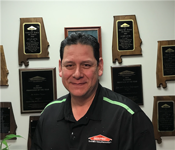 Photo of Eddie Flores in SERVPRO collared shirt with awards as backdrop
